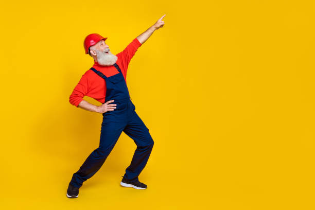istock Full length photo of nice grandpa dance boogie woogie have fun point empty space dressed safety uniform isolated on yellow color background 2182448939