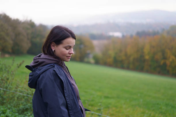 istock Girl dressed in jacket standing sideways to camera looking down smiling against blurred natural autumn landscape. Nature travel concept 2182449483