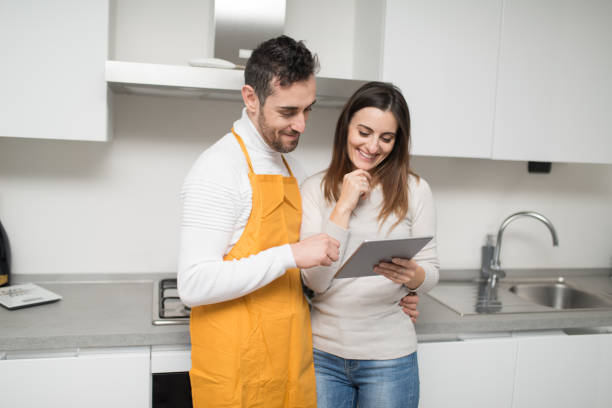 istock Happy couple browsing recipes on digital tablet in modern kitchen 2182449942