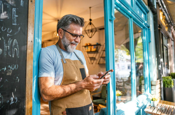 istock Mature male coffee shop owner using phone 2182454006