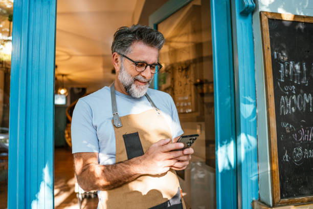 istock Mature male coffee shop owner using phone 2182454353