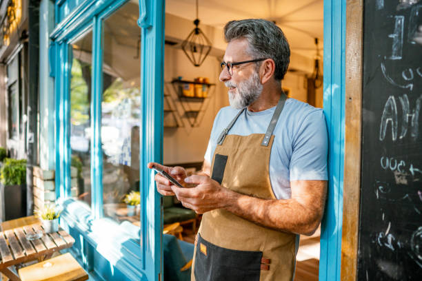 istock Mature male coffee shop owner using phone 2182454377
