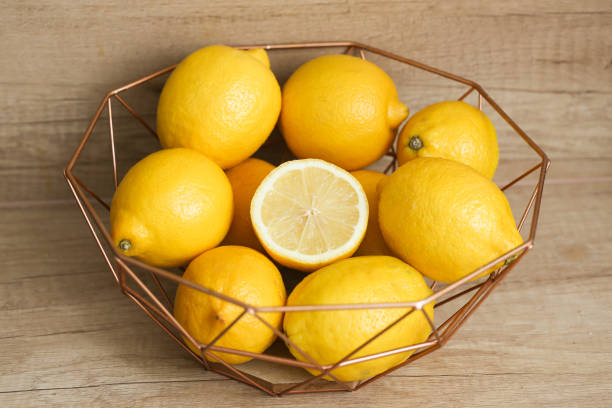 istock Lemons in a bowl on a brown wooden table. Stylish fruit display. Home interior design. Rustic kitchen setting. 2182459705