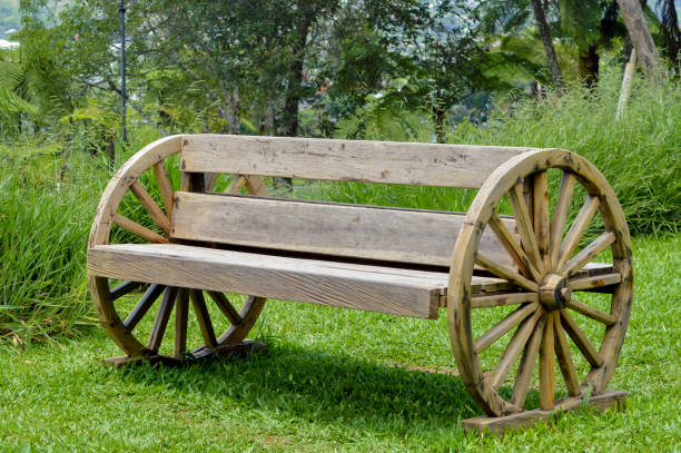 istock Rustic Wooden Bench with Wagon Wheels in Garden 2182460759