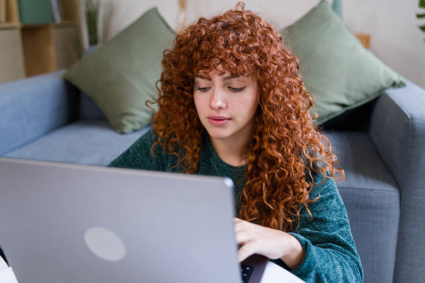 istock Focused young woman working from home using laptop, sitting on floor 2182466347
