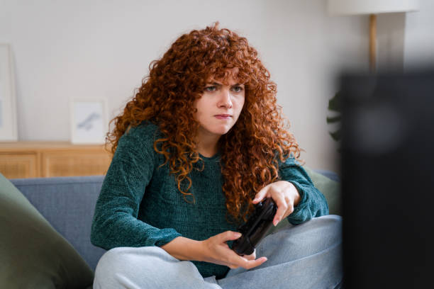 istock Focused woman playing videogames on sofa at home intensely 2182468978