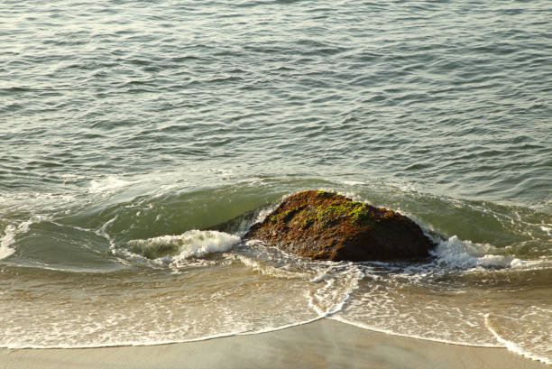 istock Ocean waves crashing over isolated rock 2182471038