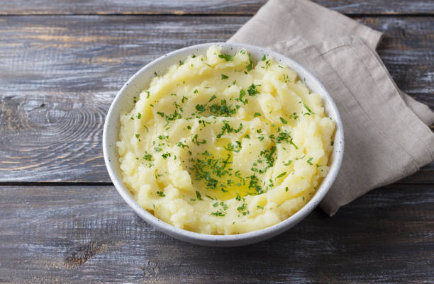 istock Mashed potatoes with melted butter and herbs in a gray ceramic bowl on a wooden table 2182472499