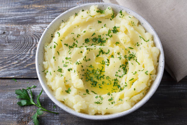 istock Mashed potatoes with melted butter and herbs in a gray ceramic bowl on a wooden table 2182472500