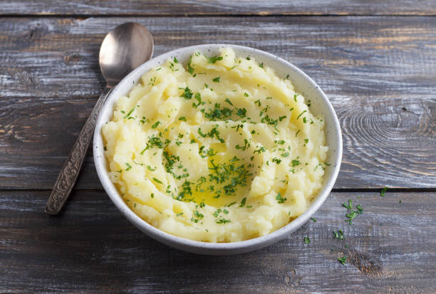 istock Mashed potatoes with melted butter and herbs in a gray ceramic bowl on a wooden table 2182472504