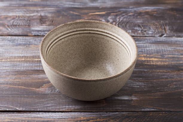 istock Simple empty beige craft ceramic bowl on wooden table, rustic style, mockup, for graphic design, creativity 2182472510