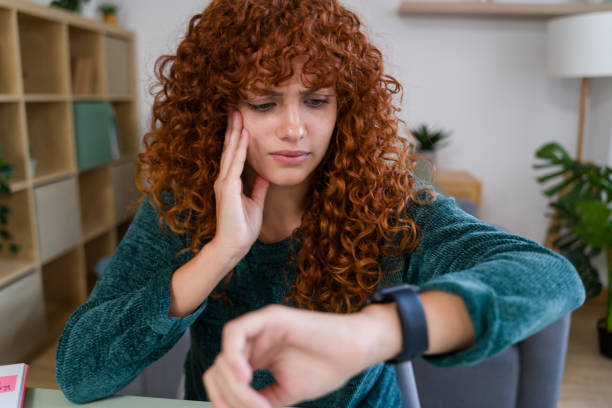 istock Stressed freelancer woman checking time on smartwatch at home office 2182473520