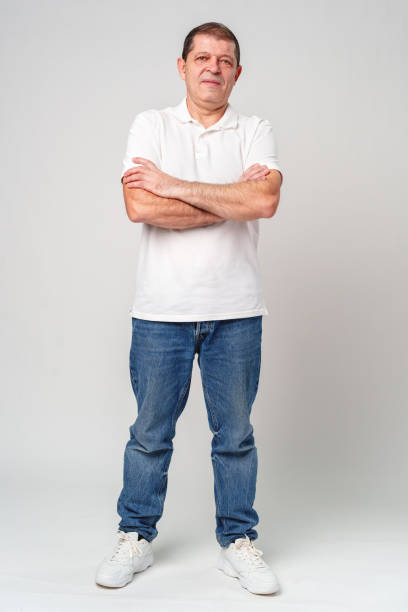 istock A man poses confidently in a white polo shirt and jeans against a light backdrop 2182474111