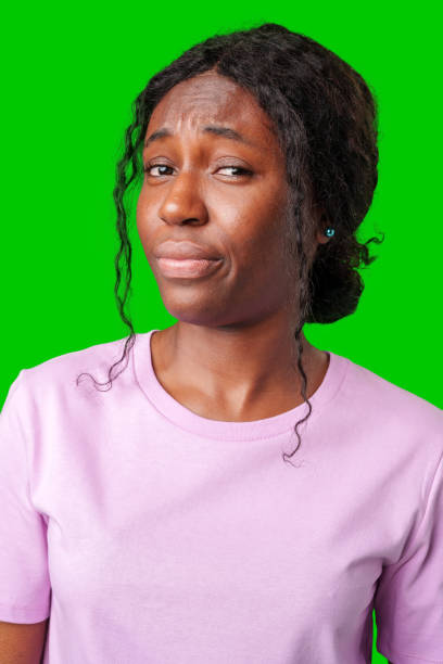 istock Young woman with curly hair shows a skeptical expression against a bright green background 2182475371