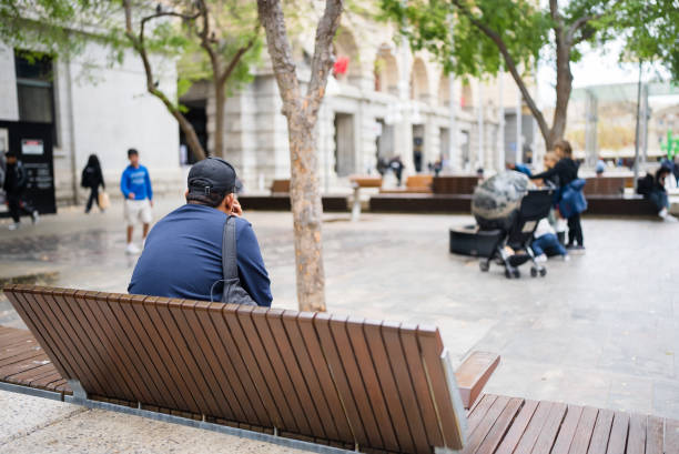 Middle-aged man using smartphone while sitting on bench in city street