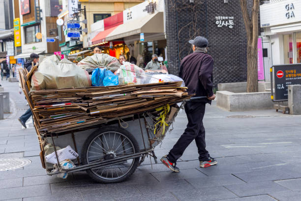 pushing a cart loaded with cardboard in seoul street - double_p stockfoto's en -beelden