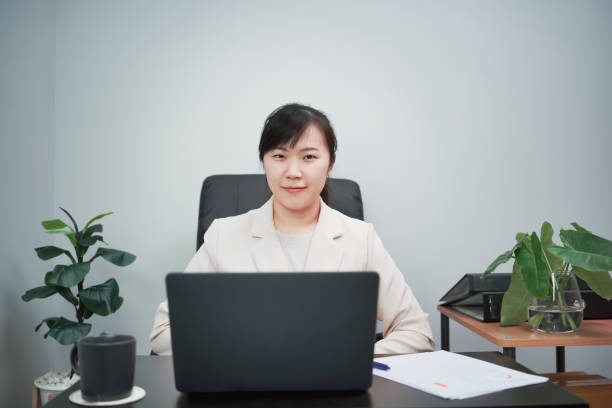 istock Woman typing work on laptop and checking work on paper as well 2182481239