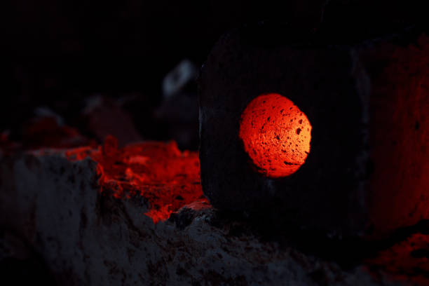 A brick with a hole in it is lit up by a small flame. The image has a moody and mysterious feel to it, as the brick appears to be glowing in the dark. The contrast between the dark background