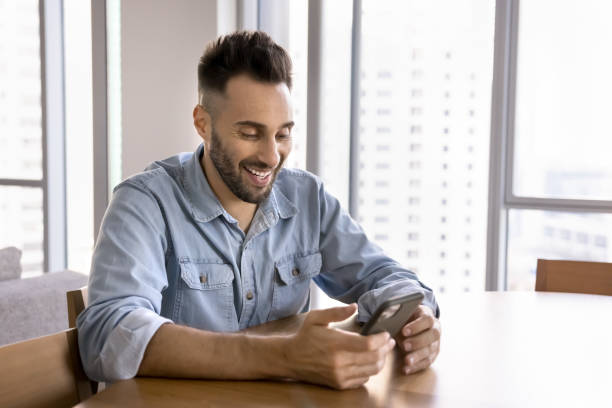 istock Cheerful handsome Hispanic man playing online game on smartphone 2182496704