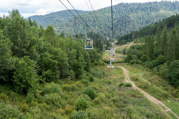 Ski lift in green forest. Cableway in Mountains. Summer nature outdoor trees