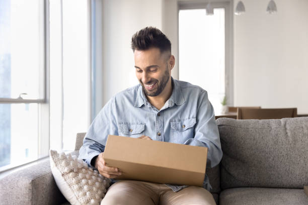 istock Cheerful Latin customer man unpacking received parcel 2182498700