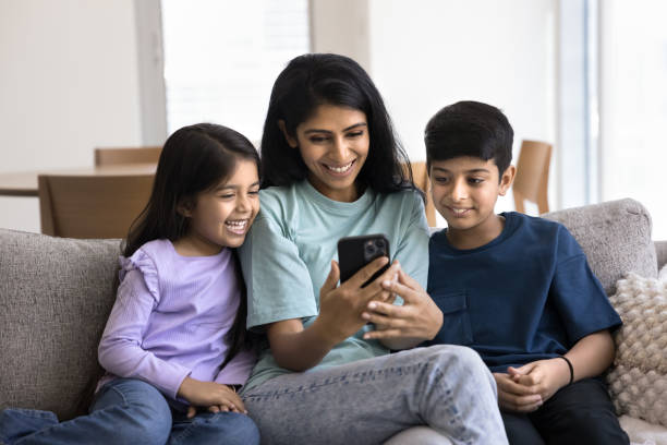 istock Happy young Indian mom and two kids watching online application 2182499672