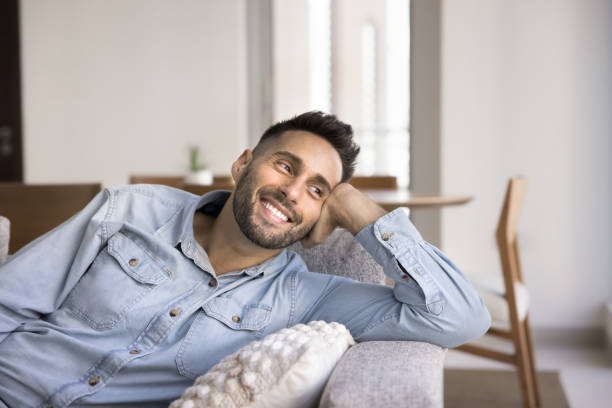 istock Cheerful handsome Hispanic homeowner guy resting on comfortable home sofa 2182500480