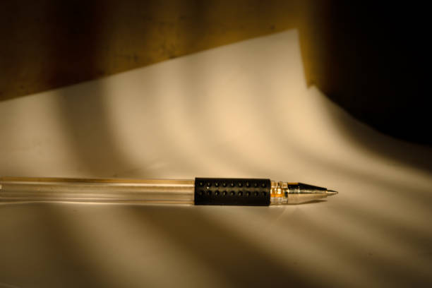 A pen lies on white paper in a low light room.