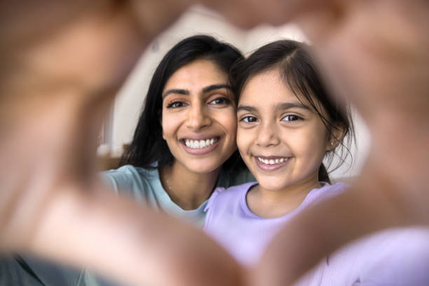 istock Happy Indian mom and kid looking at camera through heart 2182502977