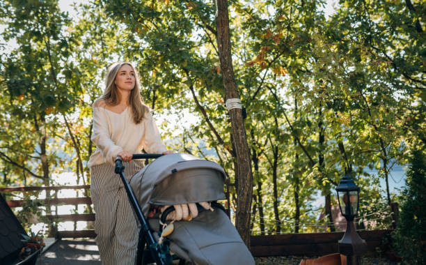 Young smiling mother taking care of her baby in the stroller