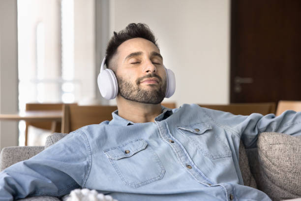 istock Hispanic man in white big headphones relaxing on home sofa 2182504303