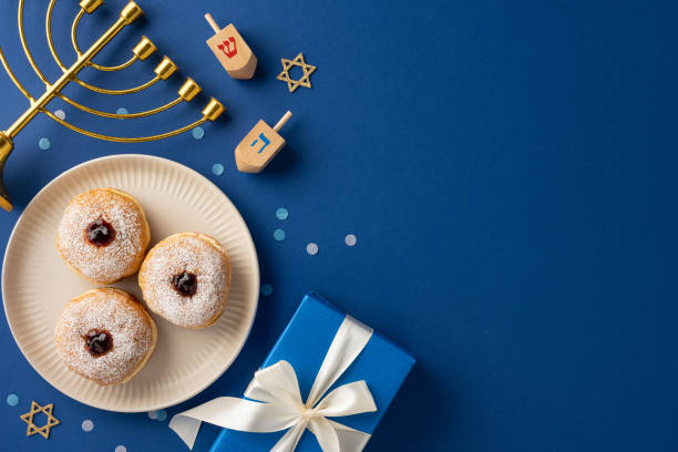 Festive Hanukkah scene showcasing a menorah, dreidels, doughnuts, and a gift on a blue background. Captures the joyful and celebratory spirit of the Jewish holiday