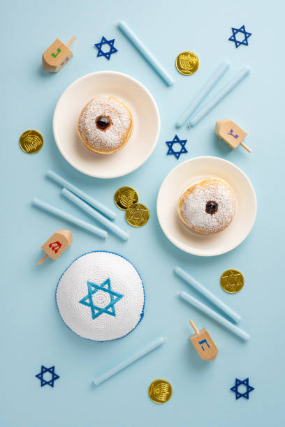 istock Festive Hanukkah vertical scene displaying traditional doughnuts, dreidels, menorah coins, and holiday symbols on a blue background 2182505559