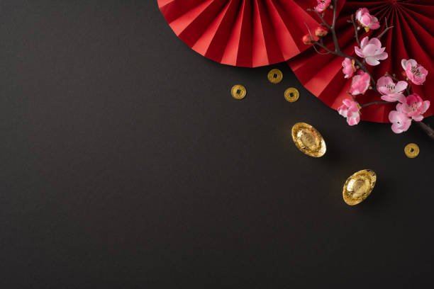 istock Festive Chinese new year composition featuring red decorations, blooming cherry blossoms, and gold ingots symbolizing prosperity and good fortune on a dark background 2182505615