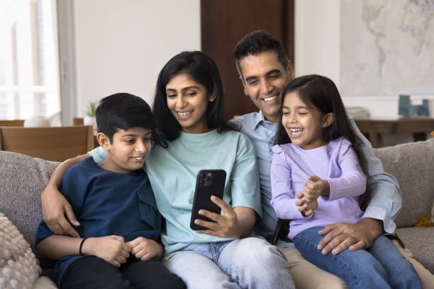 istock Happy attractive Indian mom and dad using smartphone, hugging kids 2182507842