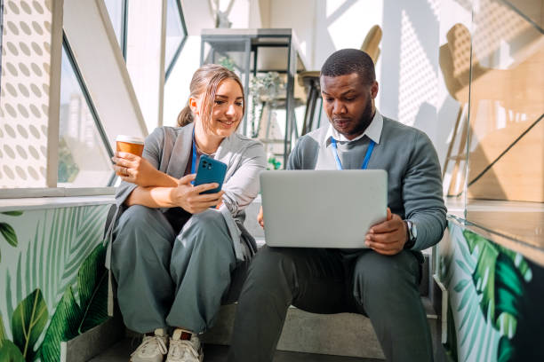istock Young adults having coffee break together at work but still trying to catch up with work looking at laptop 2182510026