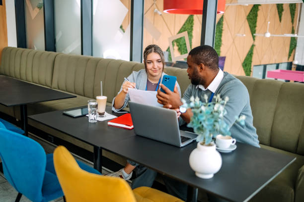 istock Young adults having coffee break together at work but still trying to catch up with work showing results looking at charts 2182510164