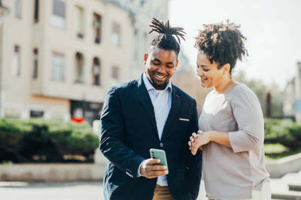 istock Two people walking together in a city environment, smiling and engaged in conversation, with modern buildings in the background 2182516530