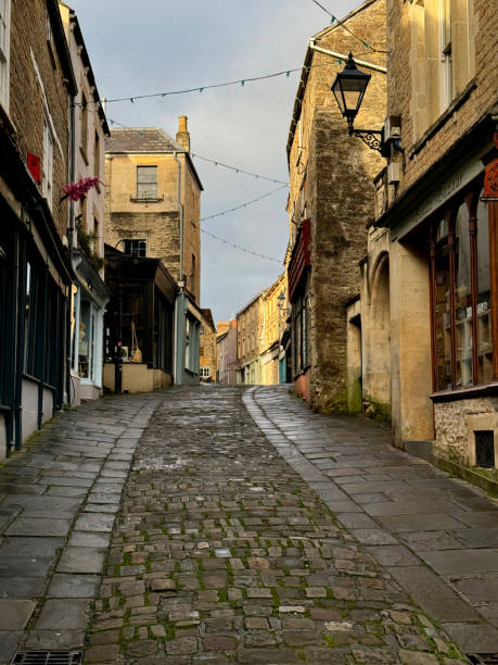 Shops and a flag stone pavement on Cheap Street in the historic town of Frome in Somerset, UK. October 2024