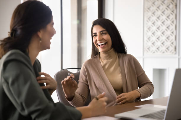istock Two happy Hispanic female office friends laughing at workplace 2182518092