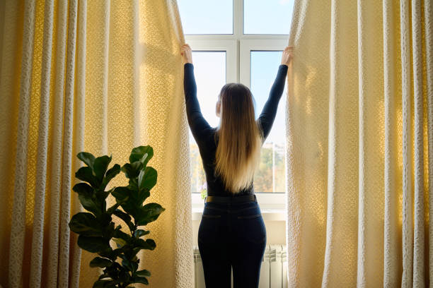 istock Young woman closing opening thick curtains on window 2182520667