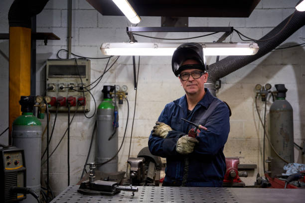 istock Welder posing with arms crossed in workshop with welding equipment 2182521297