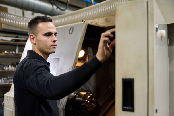 Metalworker operating a cnc machine, adjusting settings and performing quality control in a factory workshop environment