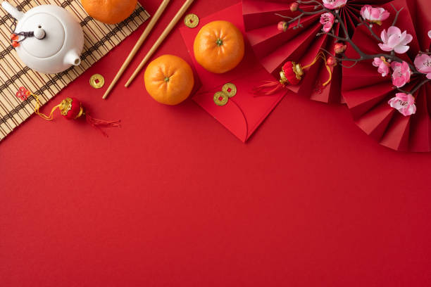 istock Festive Chinese New Year decorations with a teapot, oranges, red envelopes, and flowers on a vibrant red background 2182522012