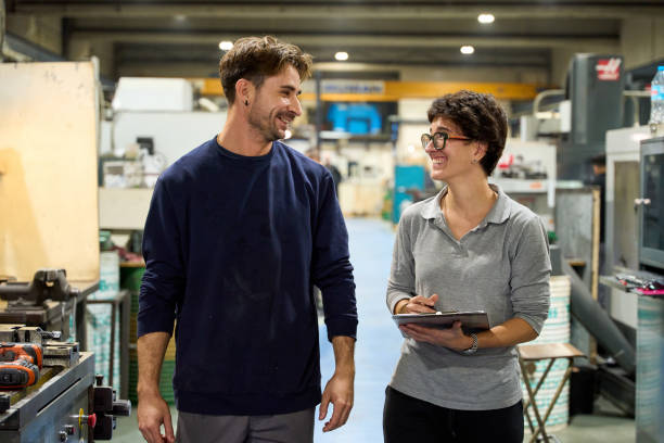 istock Smiling workers walking and talking in a factory 2182522503