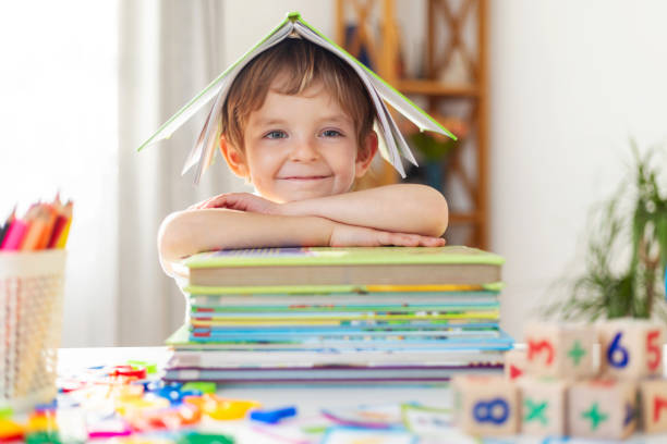 istock Smiling child under book roof at desk 2182525033
