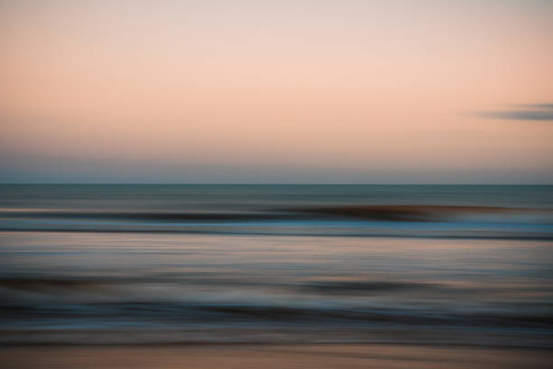 istock Softly blurred ocean waves under a peach and blue evening sky. 2182532647