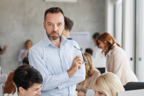 istock Confident Businessman in Office Amidst Busy Team Collaboration 2182537196