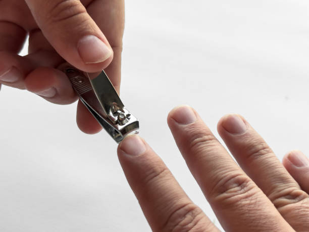 istock Close up of hand using nail clipper for personal grooming on white background 2182548562