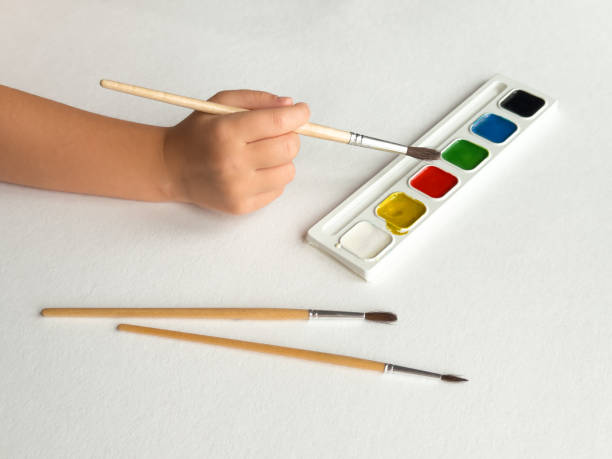 istock Creative painting. Hand holding brush over watercolor set on white canvas background 2182548666